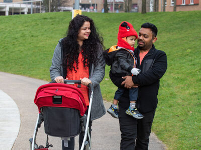 A family walking on campus with a baby and a pram