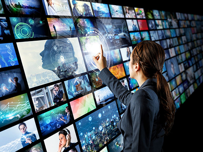 Person staring at may screens on a wall