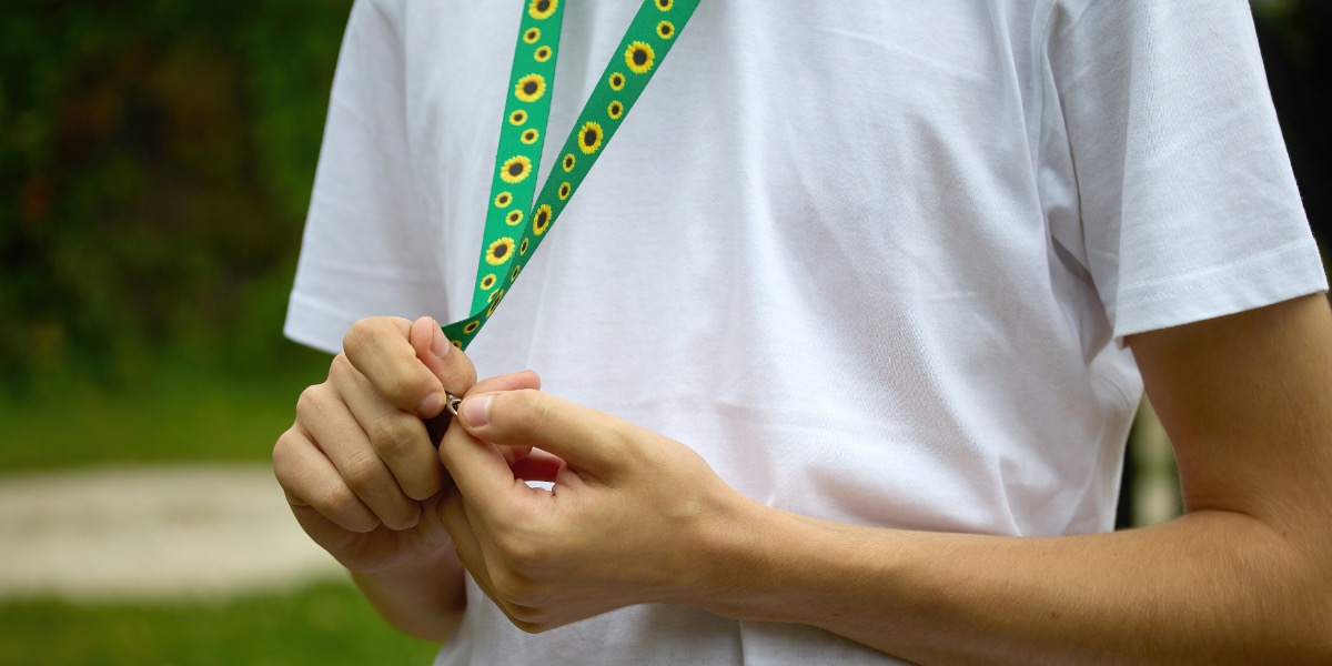 The torso of a person wearing a white t-shirt and a Sunflower lanyard.