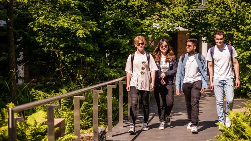 Four students walking on campus smiling