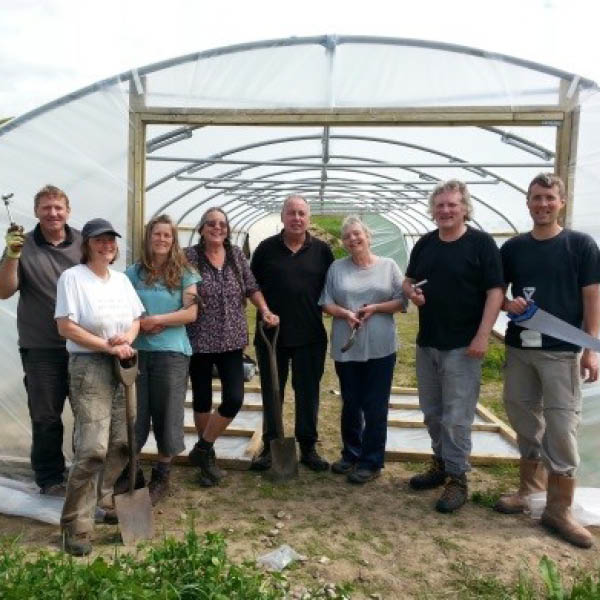 Group members standing in front of a polytunnel.