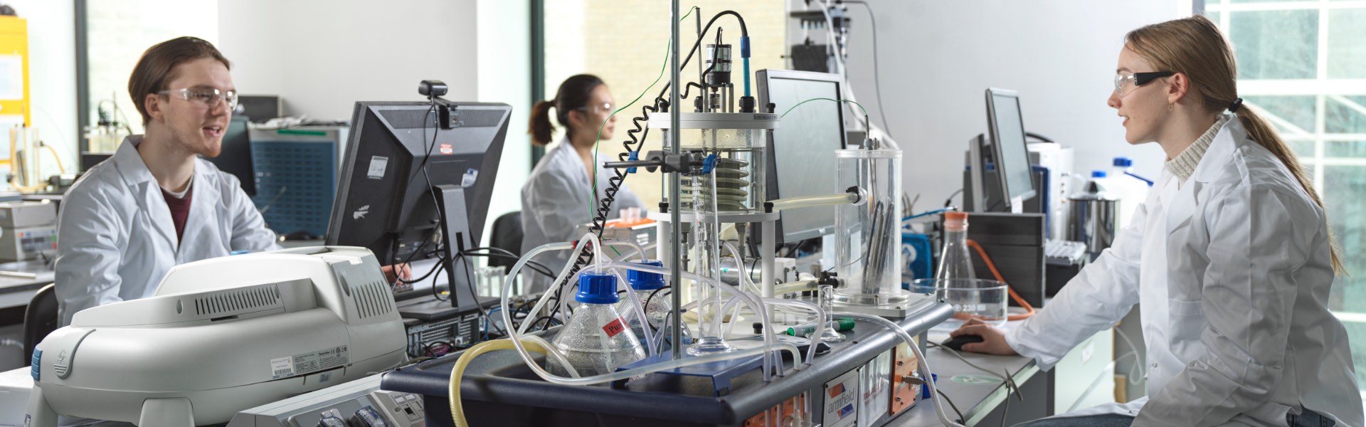 Three people work in an Engineering Laboratory.