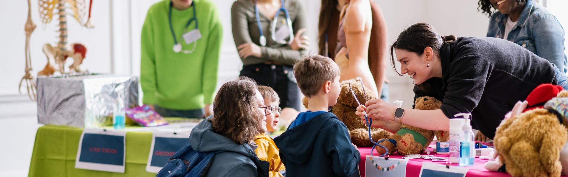 a medical student shows a family how to use a stethoscope on a teddy bear