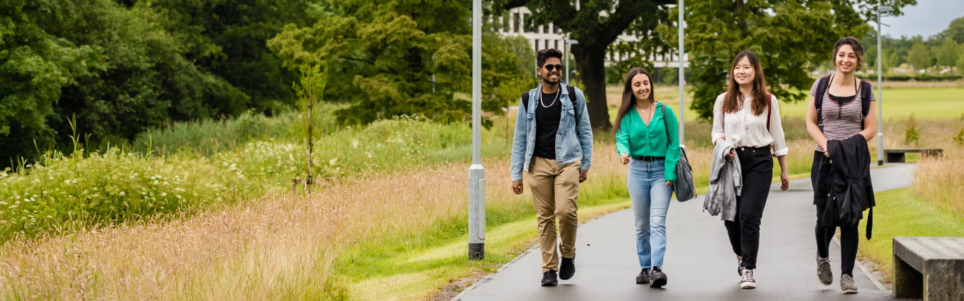 Four students walk along a path.