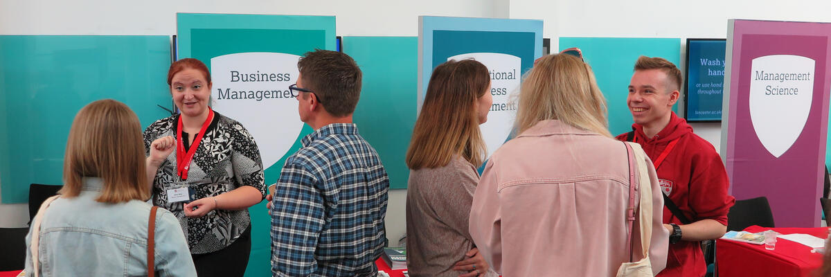A group of visitors and staff chatting at an Open Day event