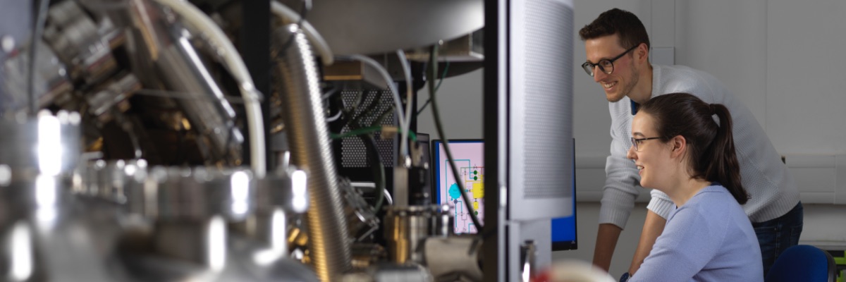 Two people operate complicated equipment in the Physics department