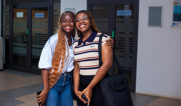 A pair of smiling female students standing outside