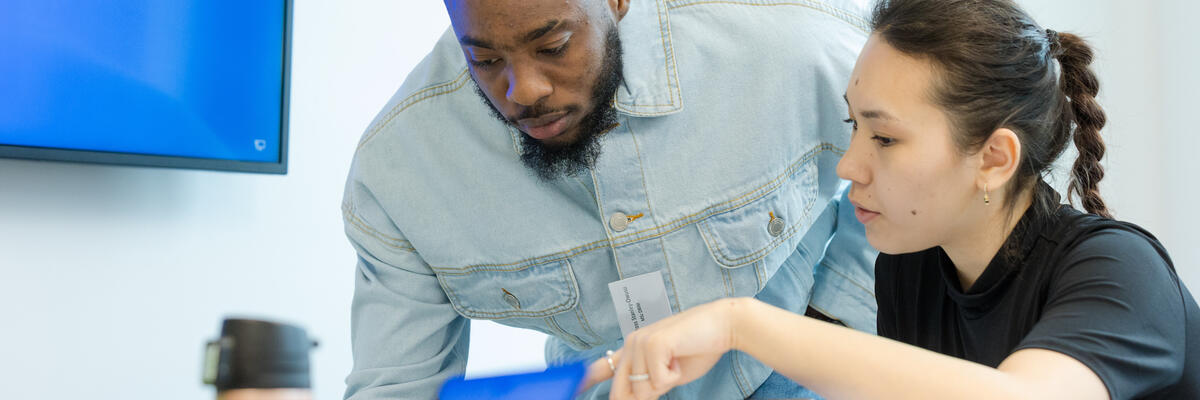 Two people discussing something they are looking at on a laptop screen