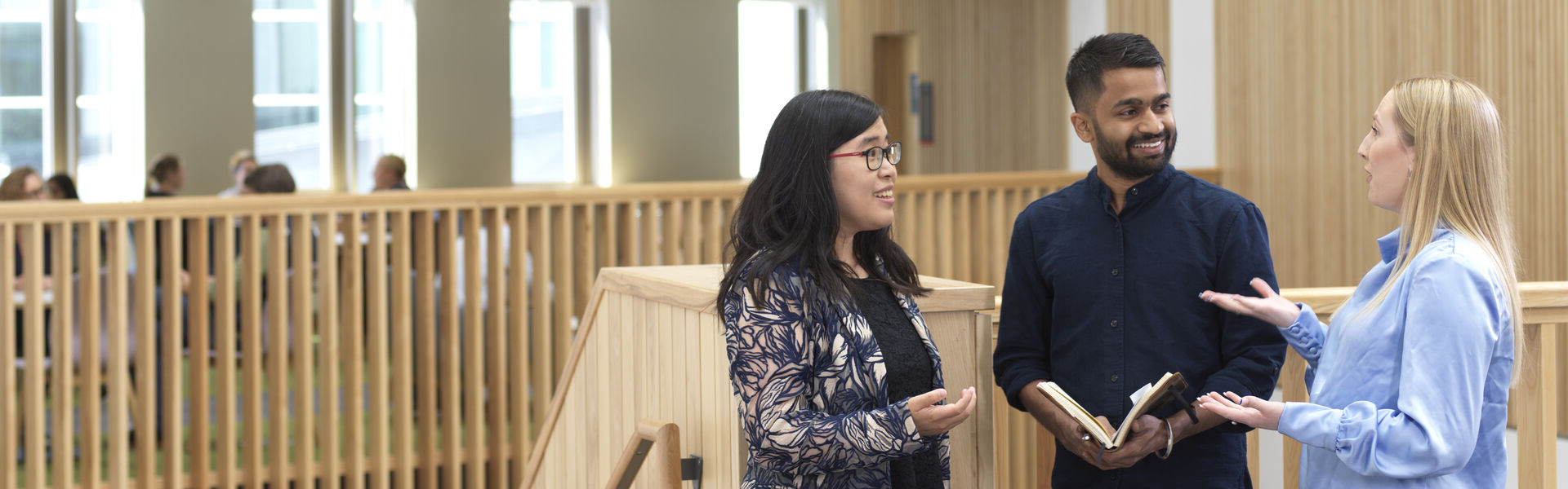 Three people standing close to each other engaged in discussion