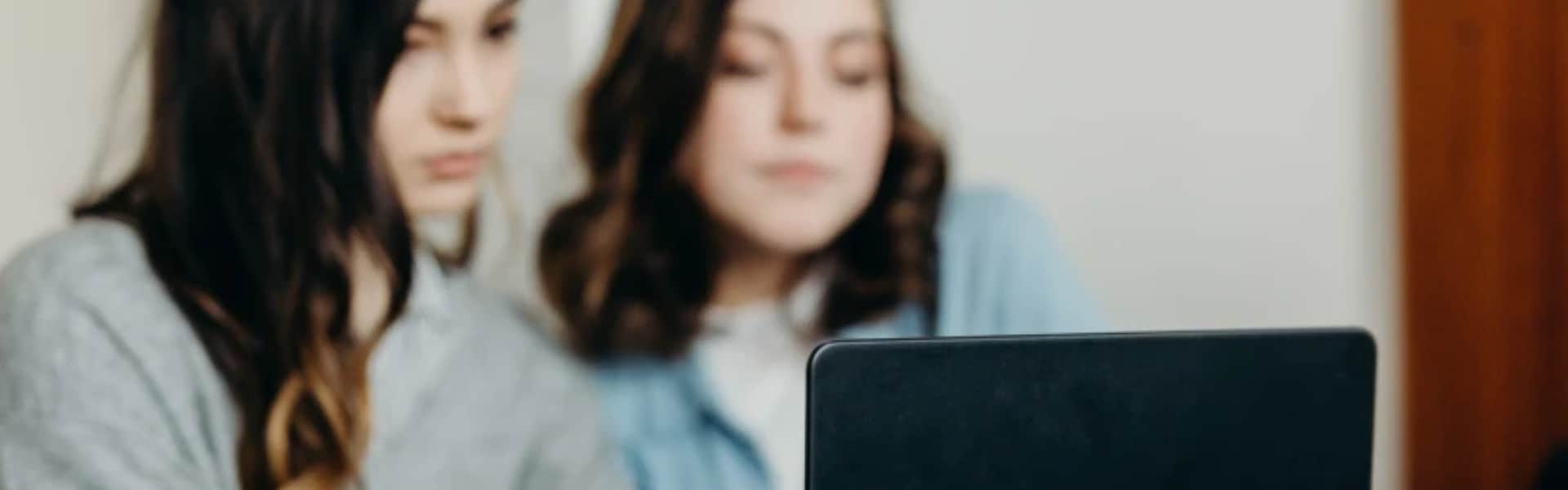 Two students sat using a laptop