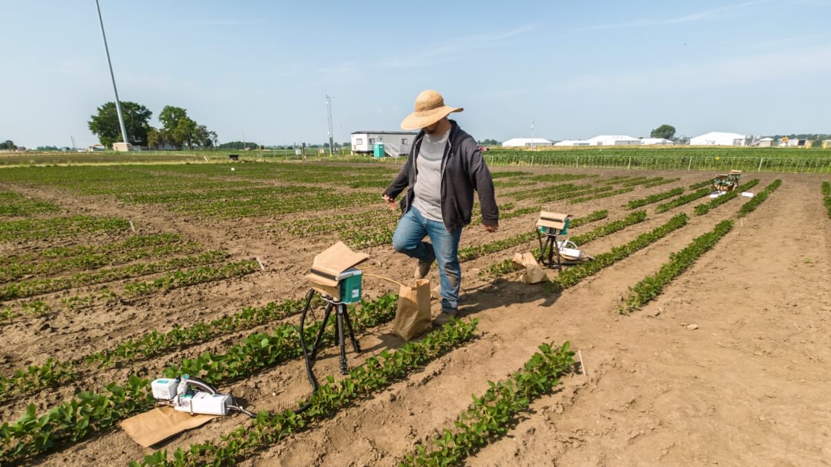 A man stands by some measuring equipment in a field.