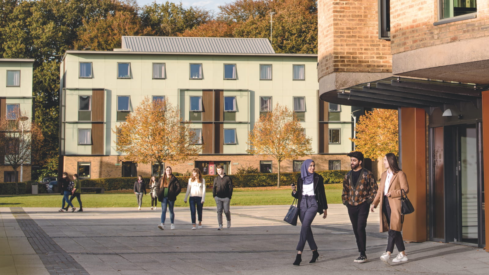 Three different groups of students walk across the open square by the Confucius Centre