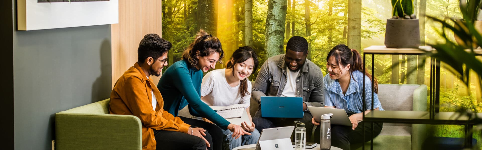 Students working together in a modern workspace with lots of plants around them.