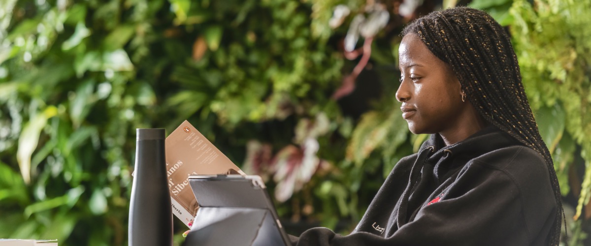 Three students are working together in the Physics atrium at a desk.
