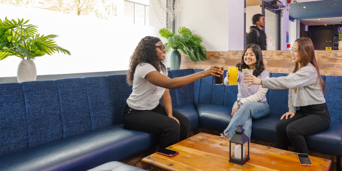 Three students clink glasses in a college bar.