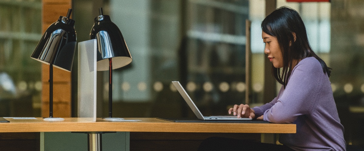 A student works on a laptop in the library.