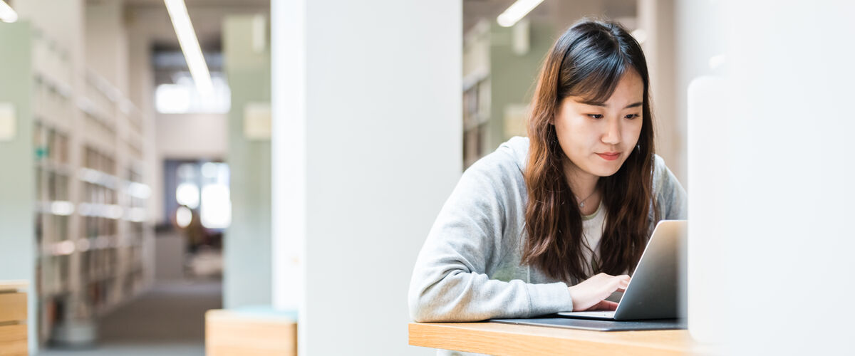 A student in the library works on a laptop.