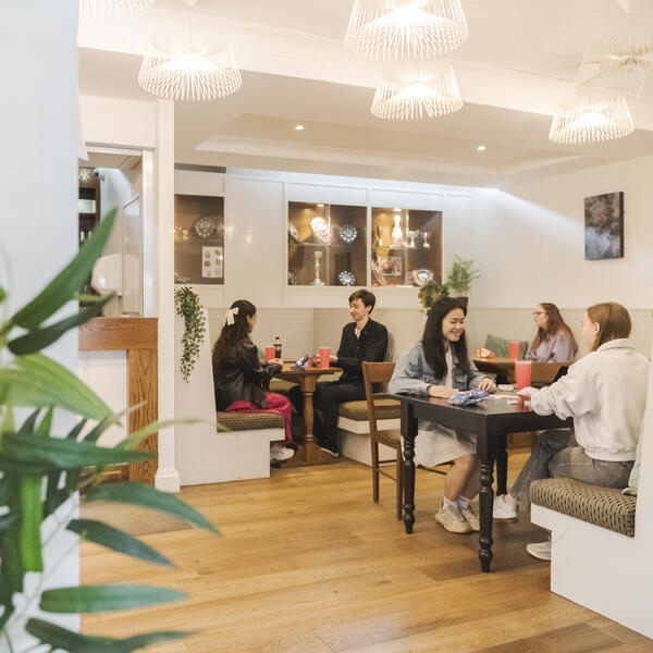 Students sit at tables in the brightly lit Bowland College social space.