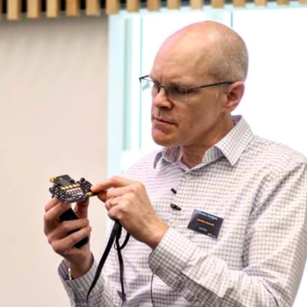 A smartly dressed man demonstrates a small, credit-card sized computer.