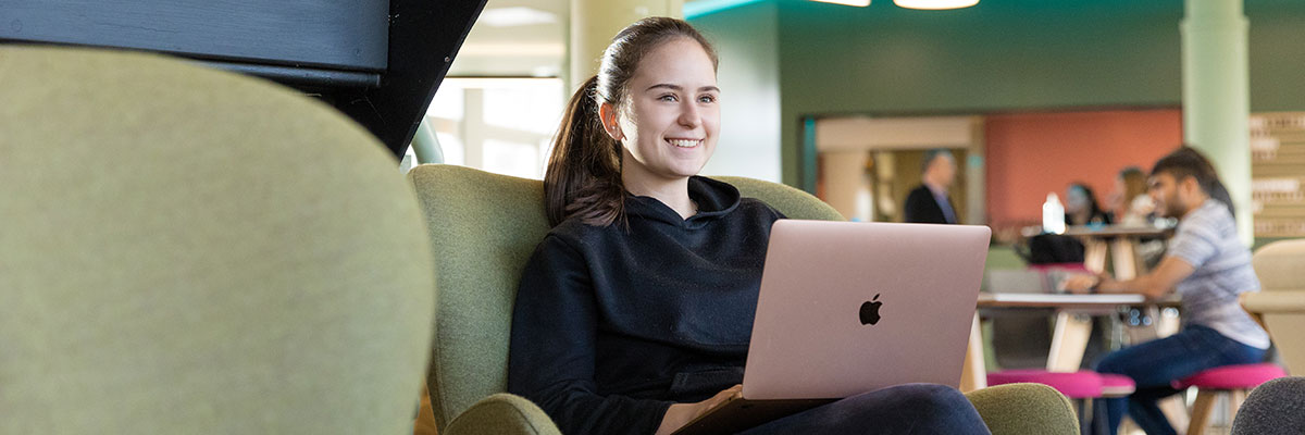 A young woman working on her laptop in a cafe.