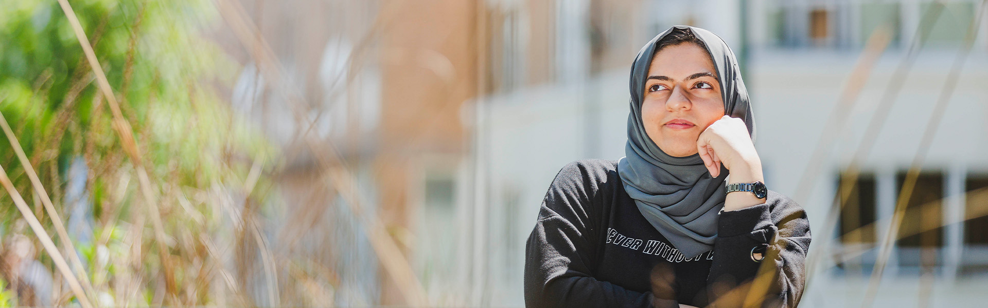 A student with a headscarf stares into the middle distance