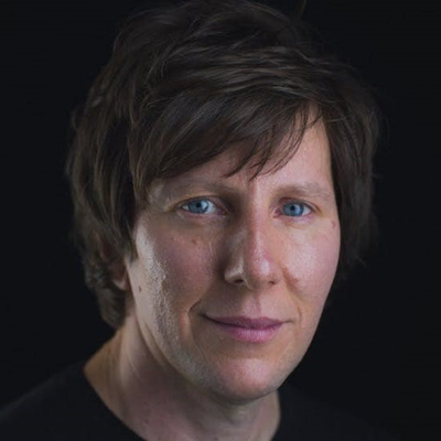 A man with medium length dark hair looking towards the camera