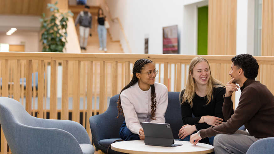 Students sat together relaxing and talking with a coffee table in the foreground